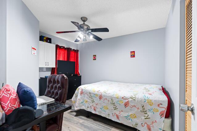 bedroom featuring light wood finished floors, a textured ceiling, and a ceiling fan