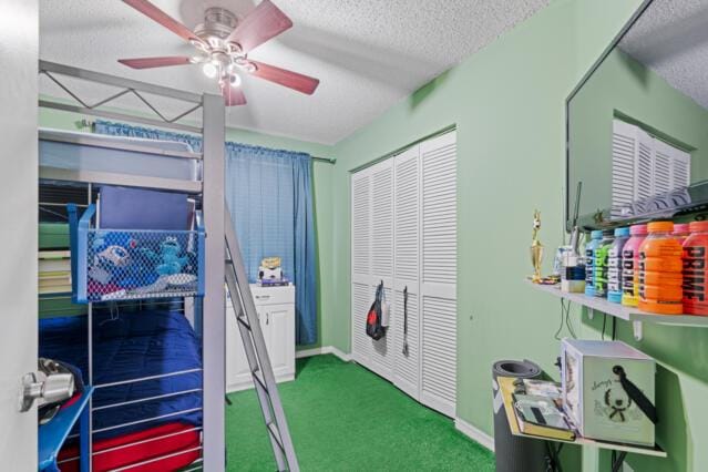 carpeted bedroom with a textured ceiling, ceiling fan, a closet, and baseboards