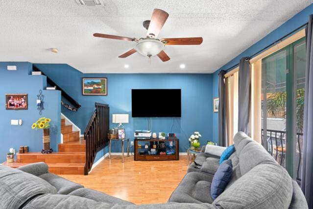 living area with baseboards, visible vents, stairway, wood finished floors, and a textured ceiling