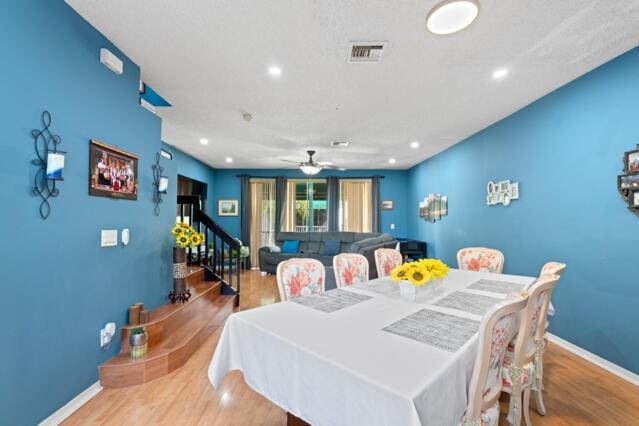 dining area featuring baseboards, visible vents, stairway, wood finished floors, and recessed lighting