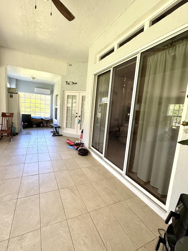 unfurnished sunroom featuring a wall mounted air conditioner and a ceiling fan