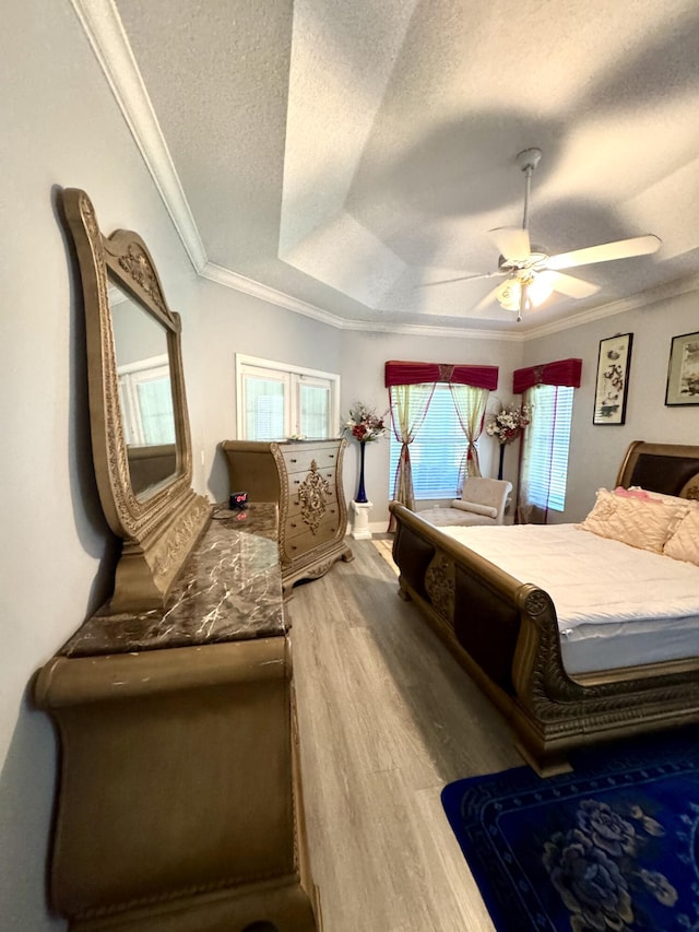 bedroom with a raised ceiling, ornamental molding, ceiling fan, a textured ceiling, and wood finished floors