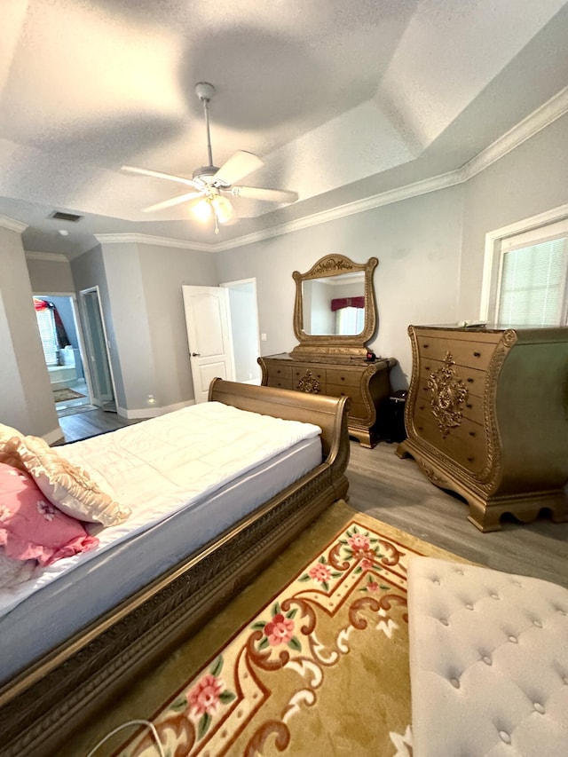 bedroom featuring a textured ceiling, ornamental molding, wood finished floors, and visible vents