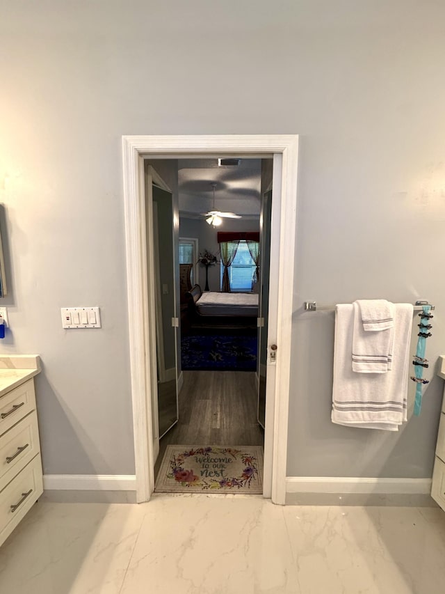 bathroom with marble finish floor, baseboards, ensuite bathroom, and vanity