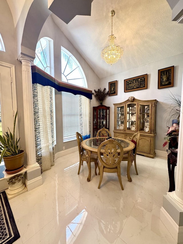 dining area featuring a chandelier, marble finish floor, decorative columns, and baseboards