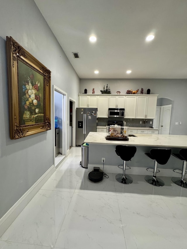 kitchen with white cabinets, stainless steel appliances, visible vents, and baseboards