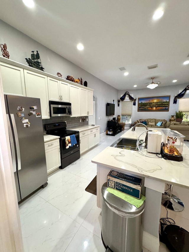 kitchen with stainless steel appliances, a sink, white cabinets, marble finish floor, and tasteful backsplash