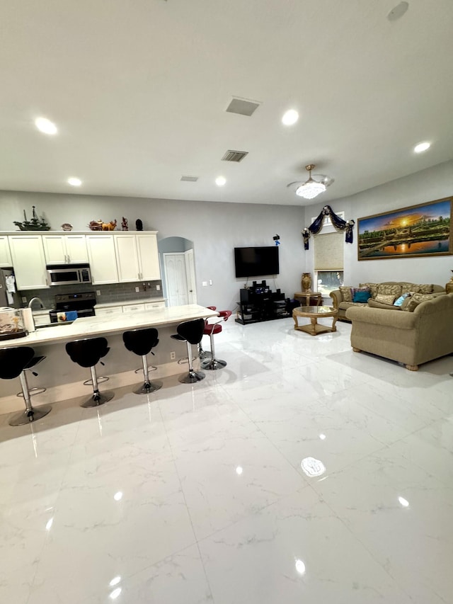 interior space featuring marble finish floor, visible vents, arched walkways, and recessed lighting