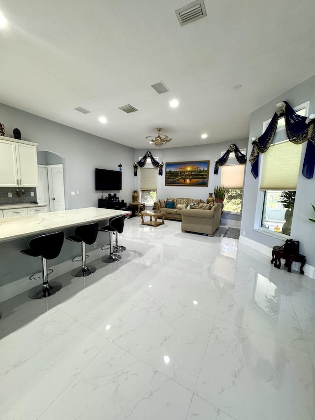 office featuring arched walkways, marble finish floor, visible vents, and baseboards