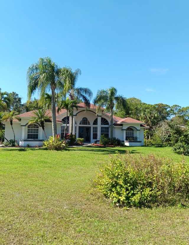 mediterranean / spanish house featuring an attached garage and a front lawn