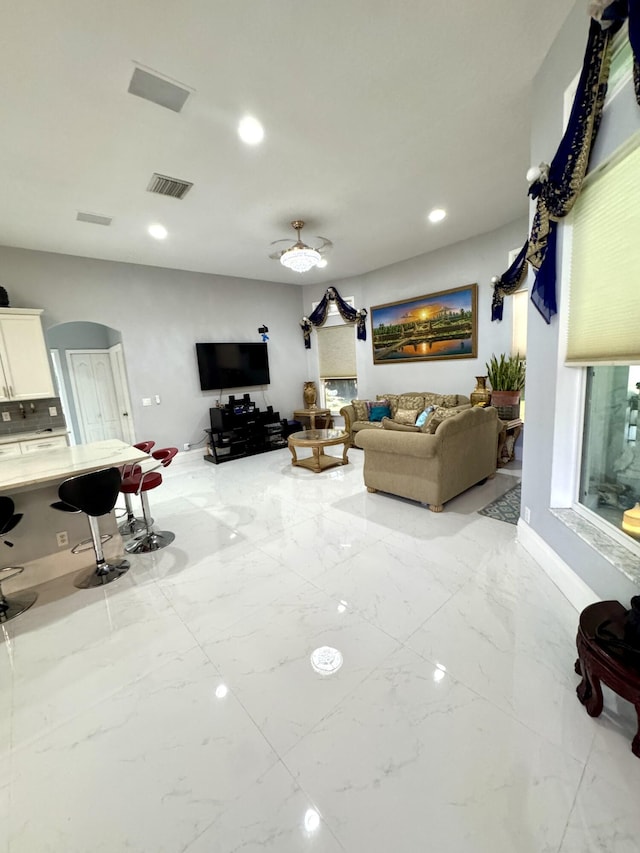 living area featuring marble finish floor, visible vents, arched walkways, and recessed lighting