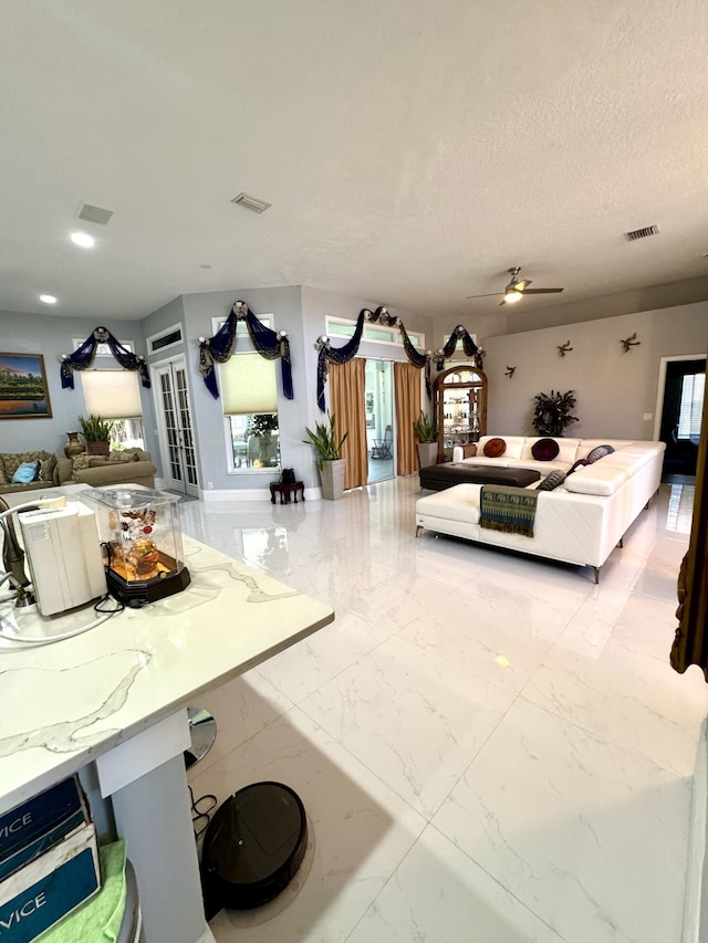 interior space featuring marble finish floor, a ceiling fan, visible vents, and a textured ceiling