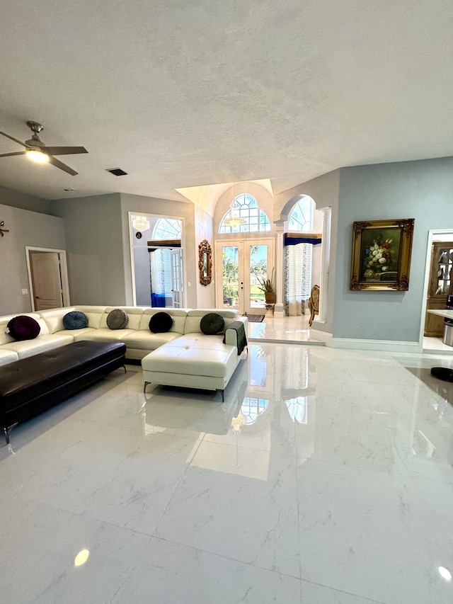 unfurnished living room with marble finish floor, french doors, visible vents, ceiling fan, and a textured ceiling