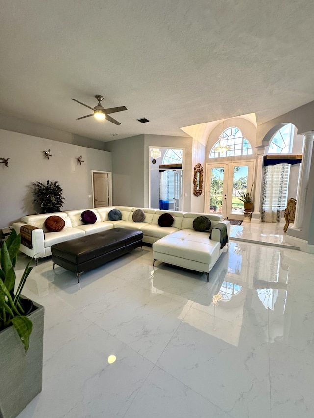 living room featuring a textured ceiling, visible vents, a ceiling fan, marble finish floor, and decorative columns