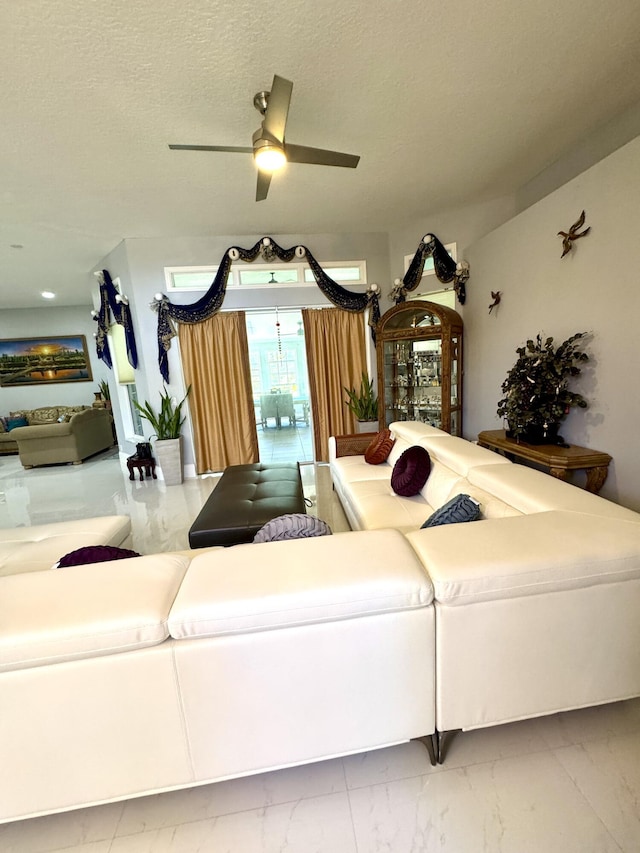 living room with marble finish floor, a ceiling fan, and a textured ceiling