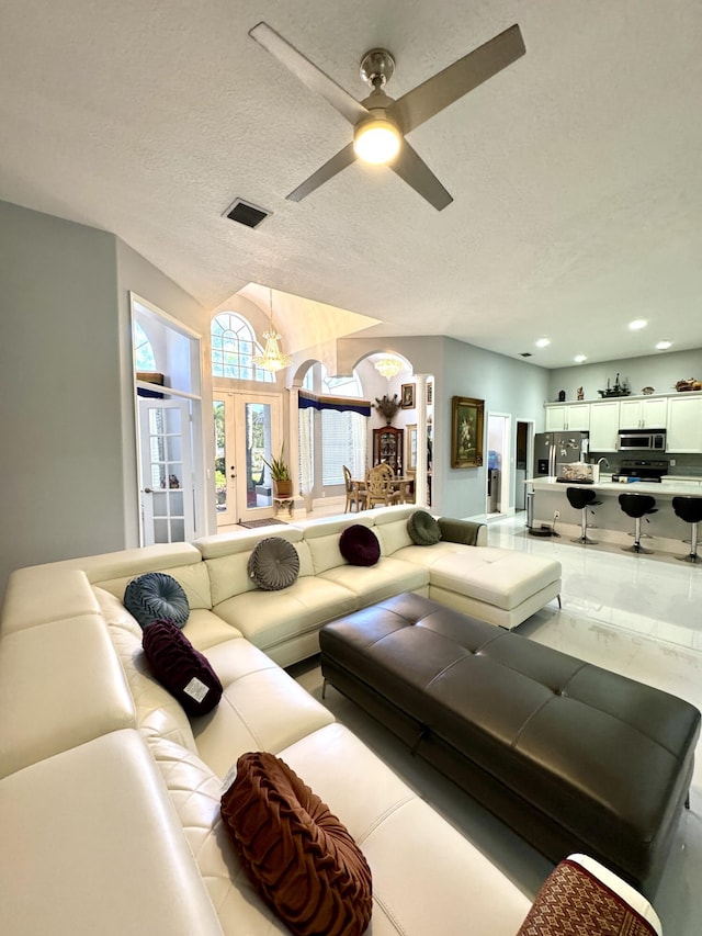 living room featuring a textured ceiling, ceiling fan, visible vents, and recessed lighting