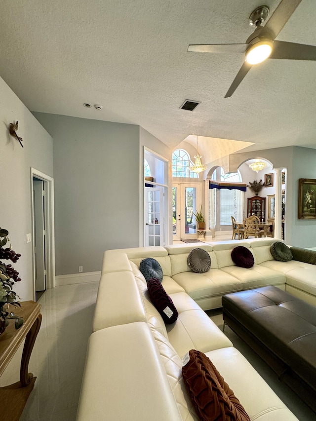 living room with visible vents, vaulted ceiling, ceiling fan, a textured ceiling, and ornate columns