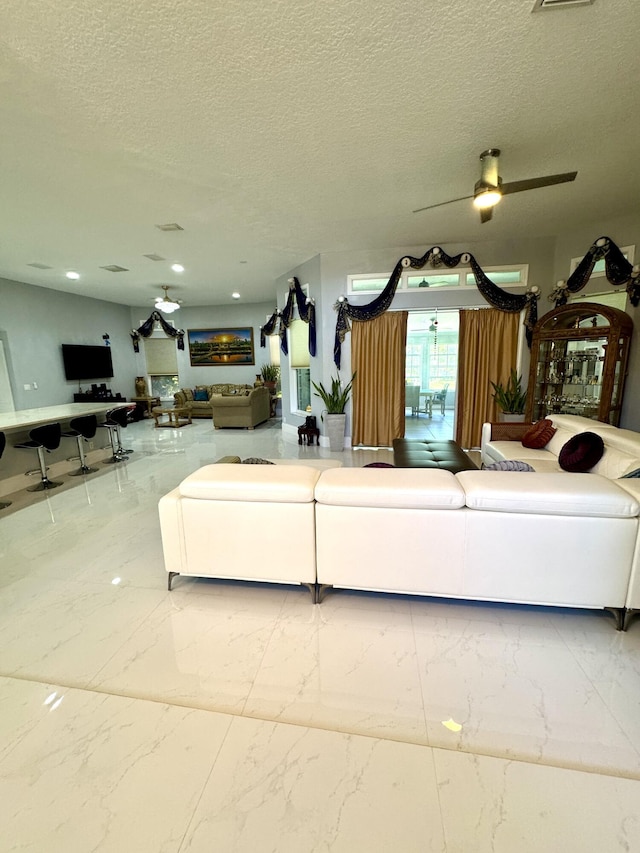 living area with marble finish floor, a textured ceiling, and a ceiling fan