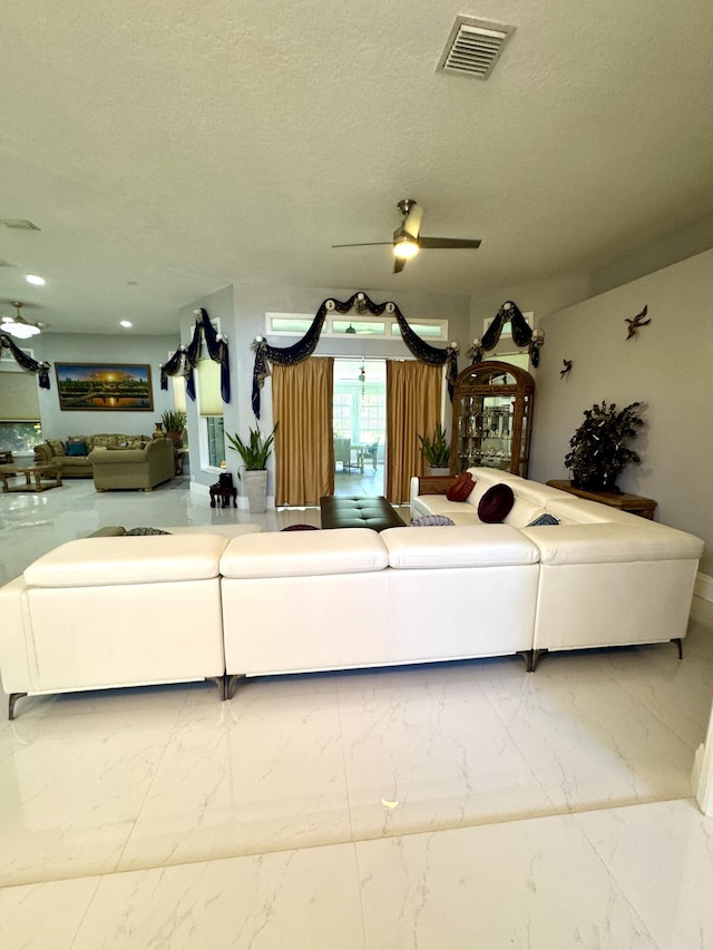 unfurnished living room with a ceiling fan, marble finish floor, visible vents, and a textured ceiling