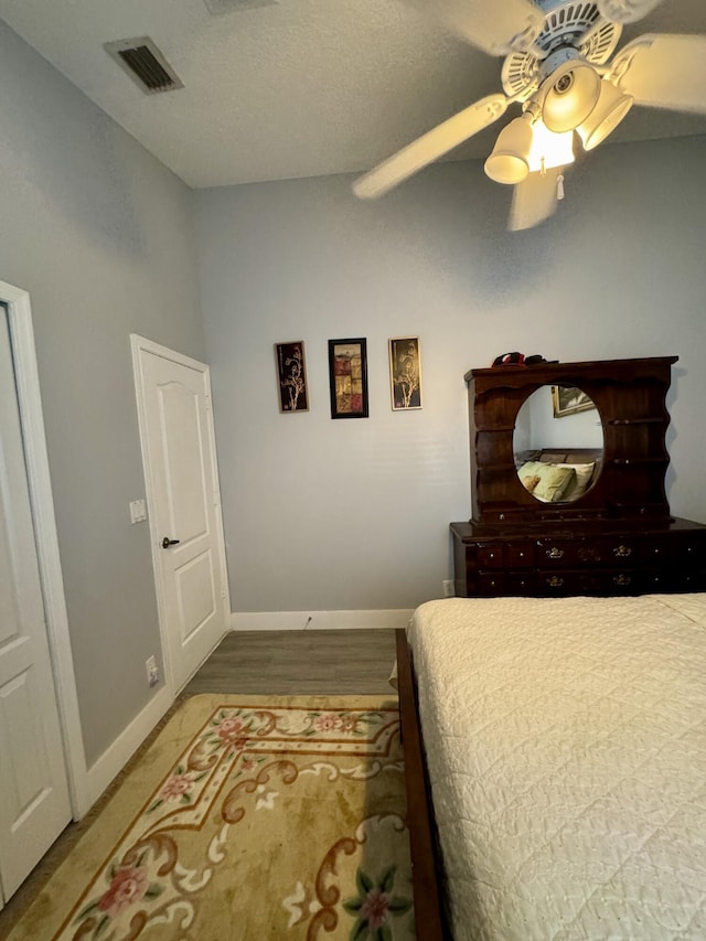 bedroom featuring baseboards, visible vents, a ceiling fan, and wood finished floors