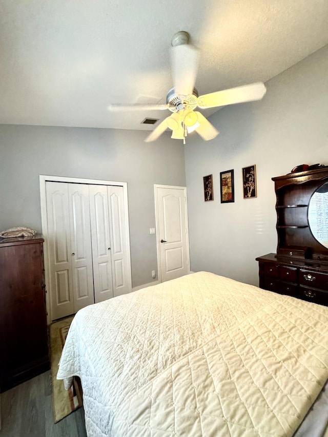 bedroom with ceiling fan, wood finished floors, visible vents, vaulted ceiling, and a closet