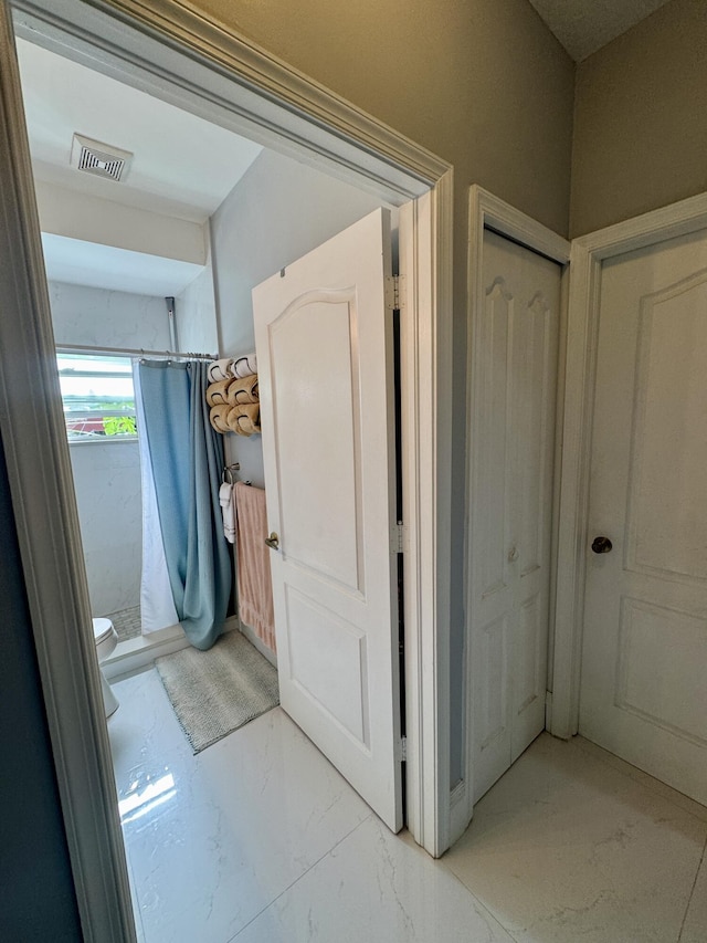 interior space featuring toilet, marble finish floor, visible vents, and a shower with shower curtain