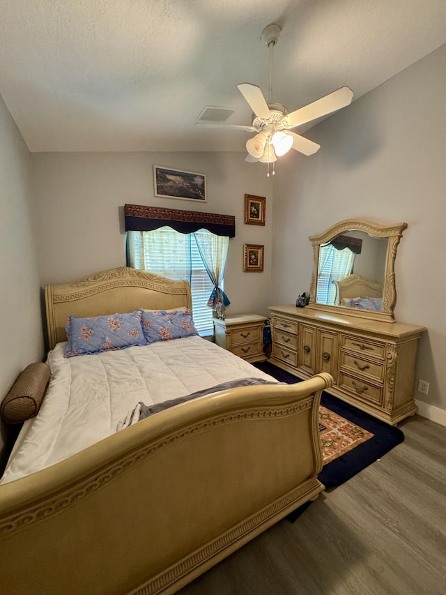 bedroom with wood finished floors, visible vents, baseboards, vaulted ceiling, and a ceiling fan