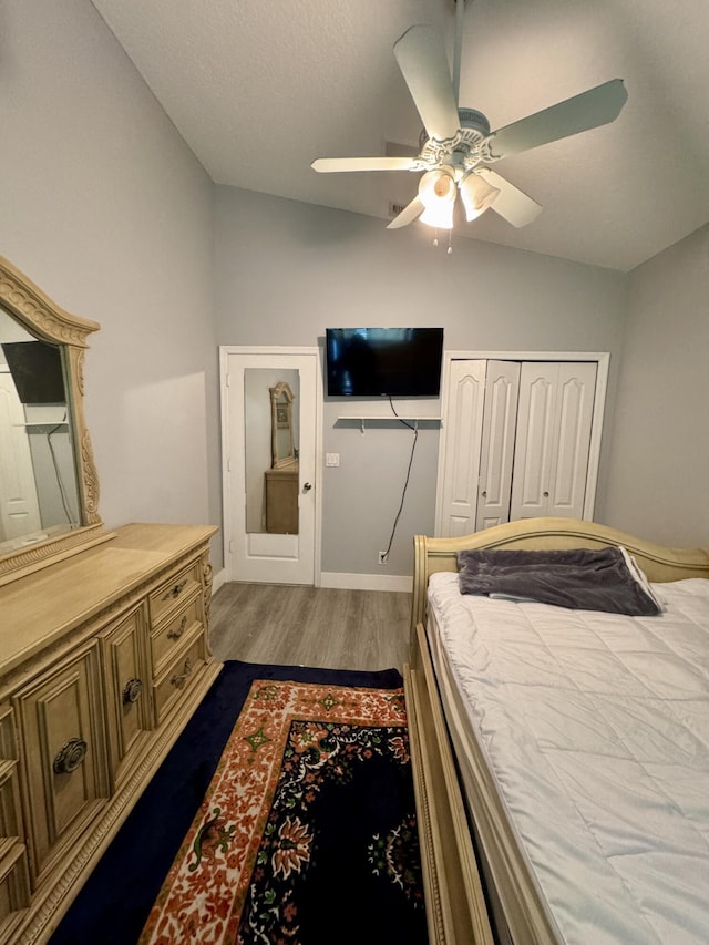 bedroom with baseboards, a ceiling fan, dark wood-style floors, vaulted ceiling, and a closet