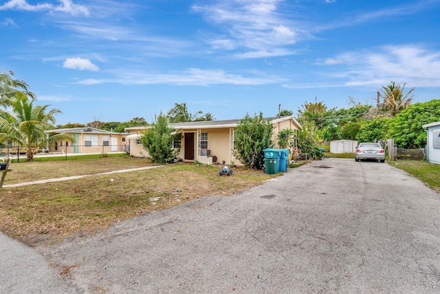 single story home with stucco siding, fence, aphalt driveway, and a front yard