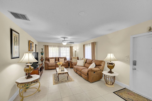 living room with a textured ceiling, light tile patterned flooring, visible vents, and baseboards