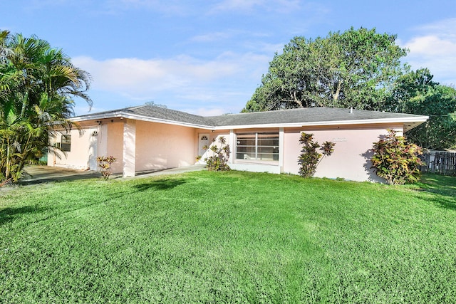 rear view of property featuring a yard and stucco siding