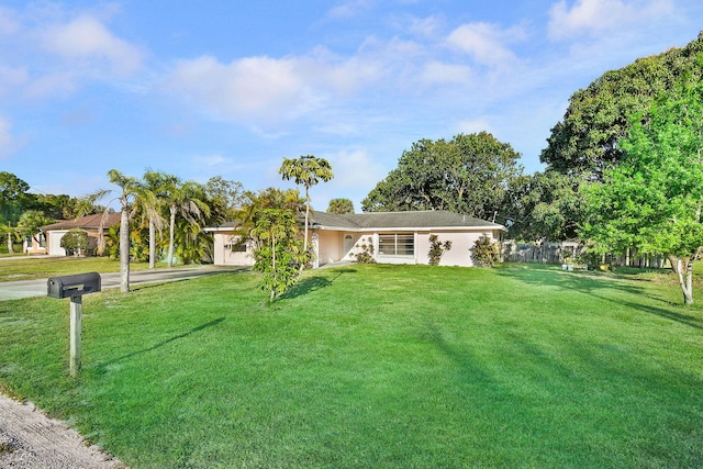 ranch-style home with an attached garage, driveway, a front yard, and fence