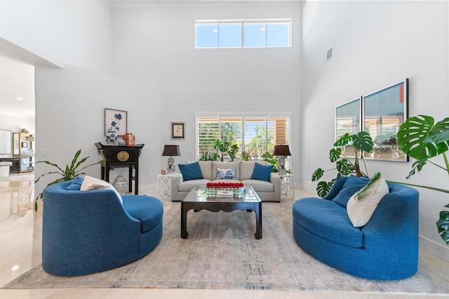 living area featuring a towering ceiling, plenty of natural light, and visible vents