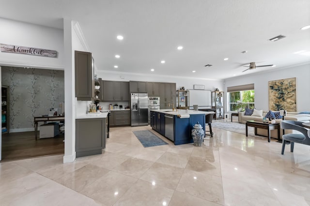 kitchen featuring appliances with stainless steel finishes, open floor plan, light countertops, and a sink