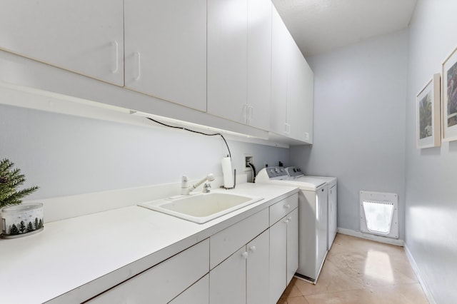 washroom featuring washer and clothes dryer, light tile patterned floors, cabinet space, a sink, and baseboards