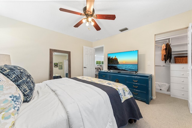 bedroom featuring light carpet, visible vents, a walk in closet, and a ceiling fan