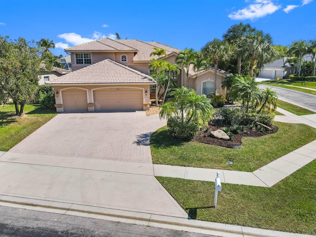 mediterranean / spanish home with decorative driveway, stucco siding, an attached garage, a front yard, and a tiled roof