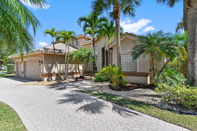 view of front of home featuring a garage, decorative driveway, a tile roof, and stucco siding