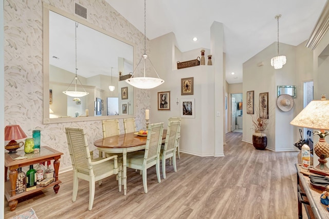 dining area with visible vents, wood finished floors, a towering ceiling, and baseboards