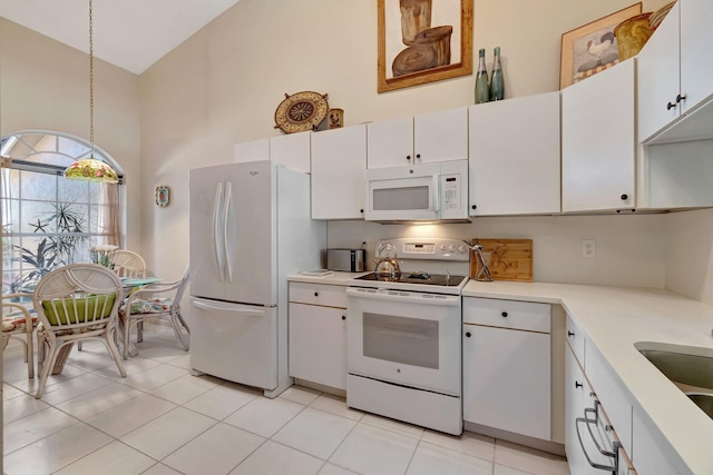 kitchen with high vaulted ceiling, white appliances, white cabinetry, light countertops, and hanging light fixtures