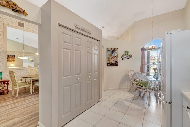 interior space featuring light tile patterned floors, high vaulted ceiling, visible vents, and baseboards