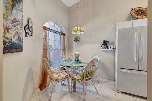 dining space with a towering ceiling, baseboards, and light tile patterned flooring