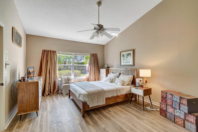 bedroom featuring light wood-type flooring, baseboards, vaulted ceiling, and a textured ceiling