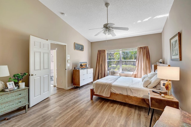 bedroom featuring light wood-type flooring, vaulted ceiling, a textured ceiling, and ceiling fan