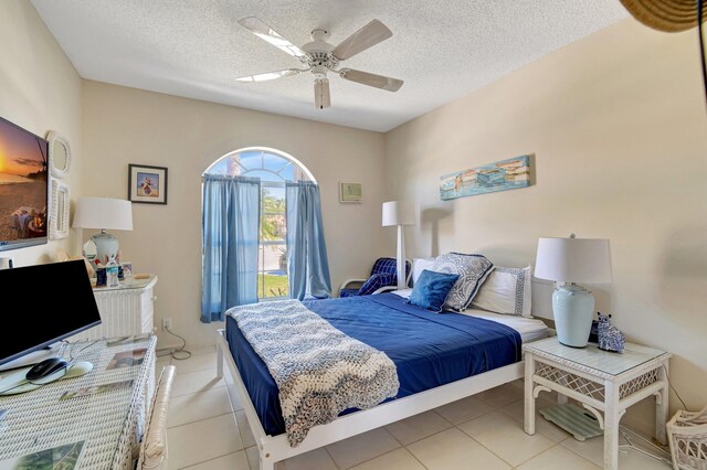 bedroom with light tile patterned floors, a textured ceiling, and a ceiling fan