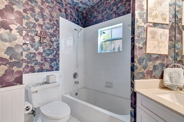 full bath with a wainscoted wall, toilet, vanity,  shower combination, and wallpapered walls