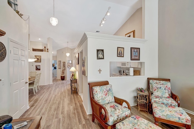 living area featuring vaulted ceiling, wood finished floors, and baseboards