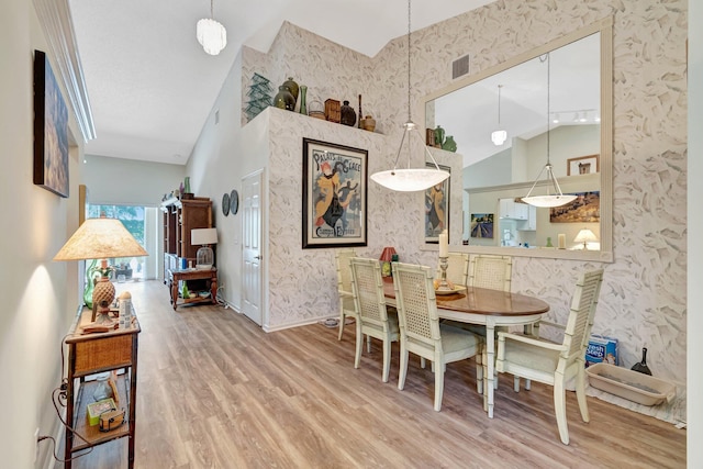 dining area with visible vents, wood finished floors, high vaulted ceiling, baseboards, and wallpapered walls