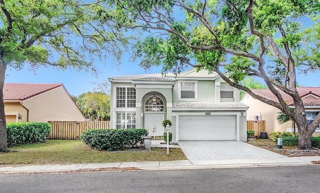 view of front facade featuring driveway, a tiled roof, an attached garage, fence, and stucco siding