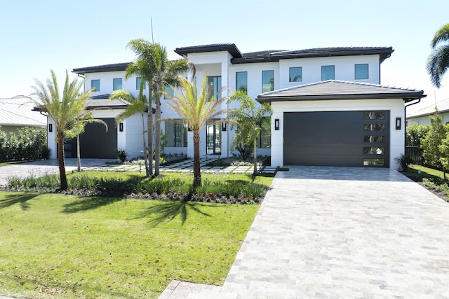 view of front facade featuring a front lawn, decorative driveway, and an attached garage